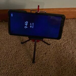 Red and black phone holder, adjustable legs, holds all phone sizes